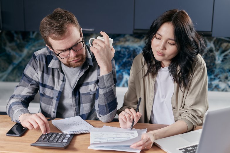 Couple reviewing home buying paperwork with a calculator at the kitchen table